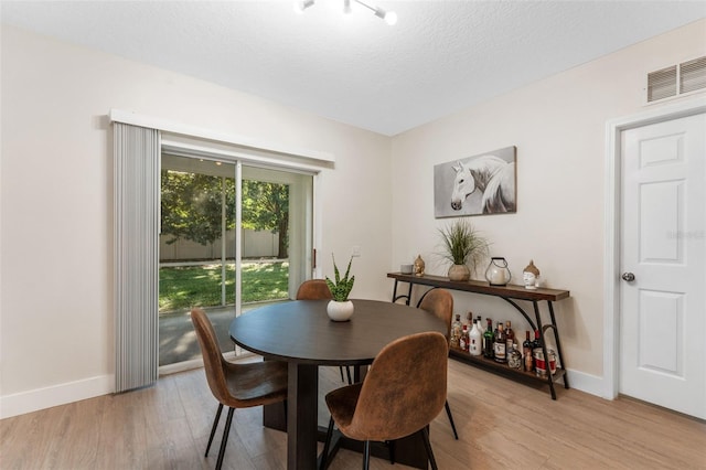 dining area with a textured ceiling and light wood-type flooring