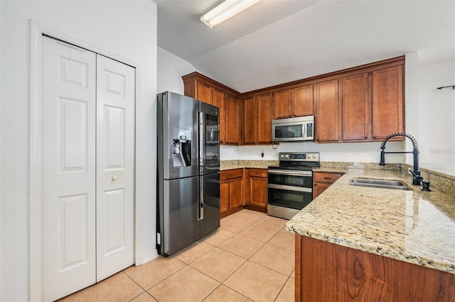 kitchen featuring sink, light stone counters, stainless steel appliances, light tile patterned floors, and a textured ceiling