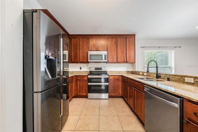 kitchen featuring sink, light stone countertops, appliances with stainless steel finishes, light tile patterned floors, and a textured ceiling