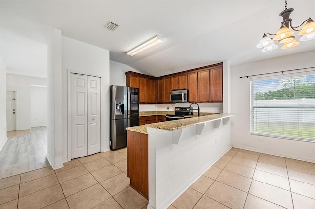 kitchen with pendant lighting, light tile patterned floors, kitchen peninsula, appliances with stainless steel finishes, and an inviting chandelier