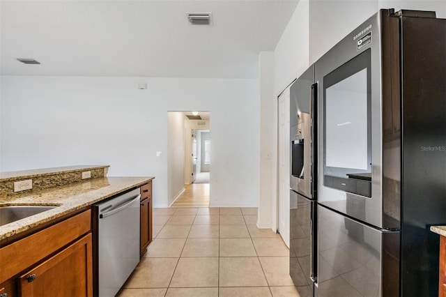 kitchen with light tile patterned floors, light stone countertops, and stainless steel appliances