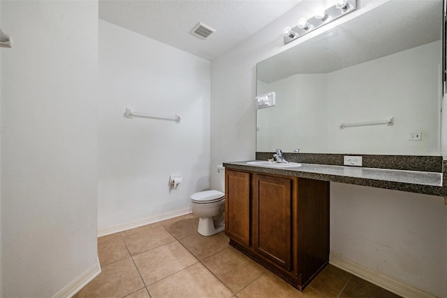 bathroom with tile patterned flooring, a textured ceiling, vanity, and toilet