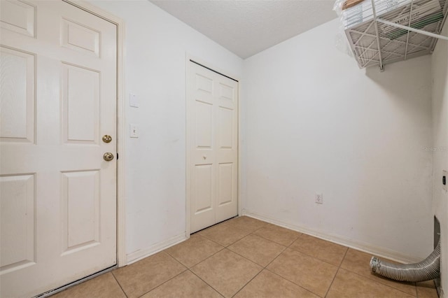 interior space featuring a textured ceiling, light tile patterned floors, and electric dryer hookup