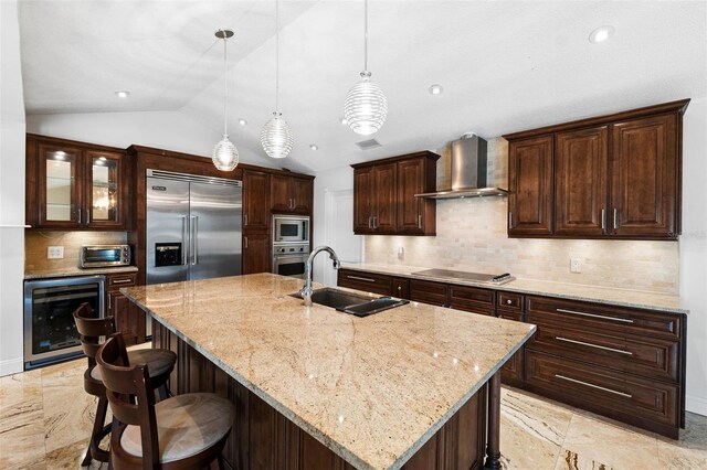 kitchen featuring wall chimney exhaust hood, a large island, sink, and built in appliances