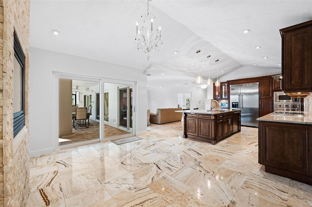 kitchen with sink, lofted ceiling, pendant lighting, built in appliances, and a center island with sink