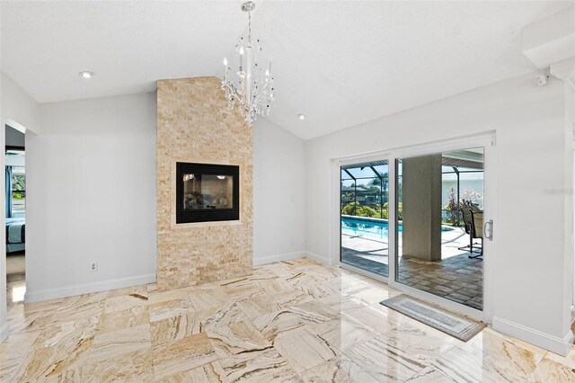 unfurnished living room with lofted ceiling, a chandelier, and a large fireplace