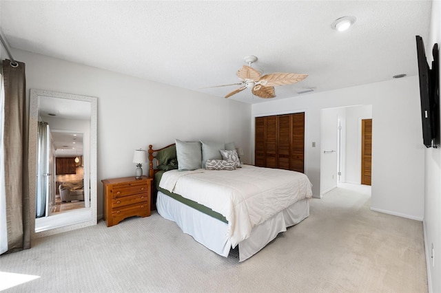 carpeted bedroom with a closet, a textured ceiling, and ceiling fan