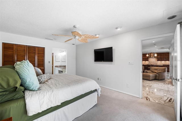 bedroom with a textured ceiling, connected bathroom, carpet, and ceiling fan