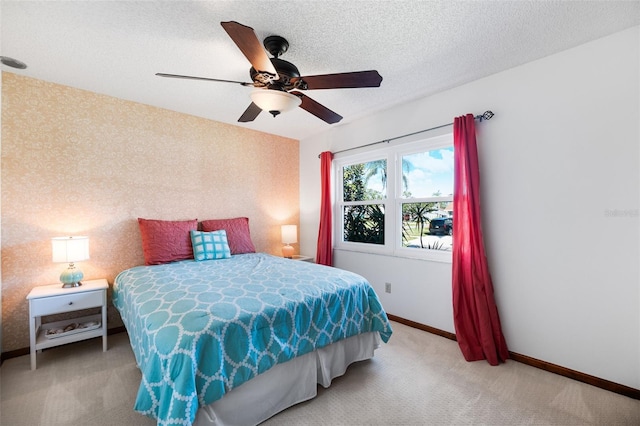 carpeted bedroom with ceiling fan and a textured ceiling