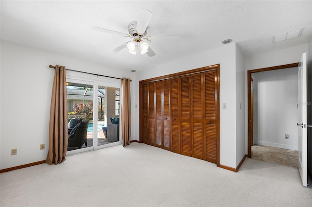 unfurnished bedroom featuring a textured ceiling, access to exterior, a closet, ceiling fan, and light colored carpet