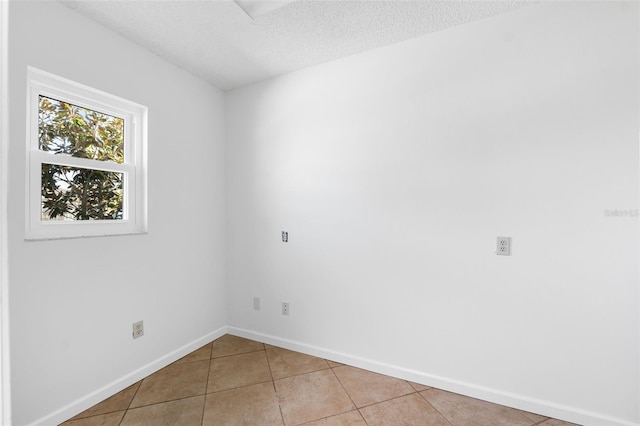 empty room with a textured ceiling and light tile patterned floors