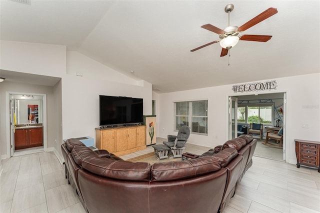 living room with ceiling fan, light tile patterned flooring, and vaulted ceiling