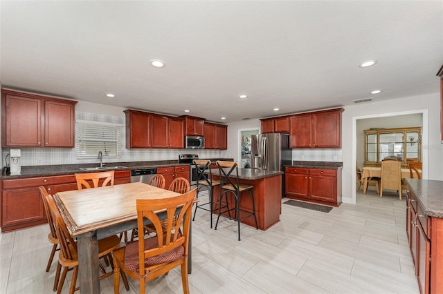 kitchen with appliances with stainless steel finishes, sink, a healthy amount of sunlight, and a kitchen island