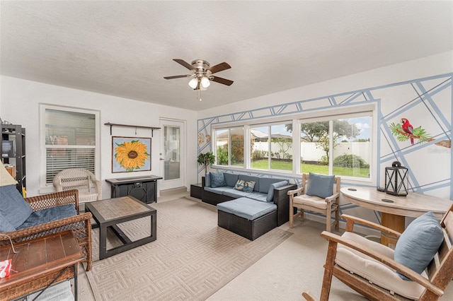 living room featuring ceiling fan, light colored carpet, and a textured ceiling