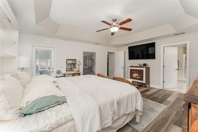 bedroom featuring a tray ceiling, light wood-type flooring, and ceiling fan