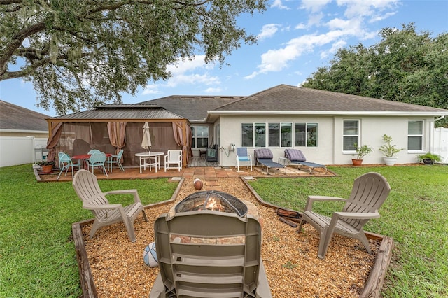 back of property with a lawn, a patio area, and an outdoor fire pit