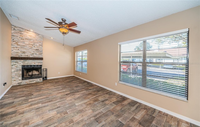 unfurnished living room with a textured ceiling, ceiling fan, a fireplace, hardwood / wood-style floors, and lofted ceiling