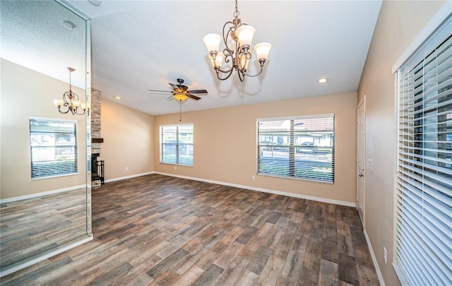 interior space featuring a textured ceiling, a stone fireplace, dark hardwood / wood-style flooring, and ceiling fan with notable chandelier