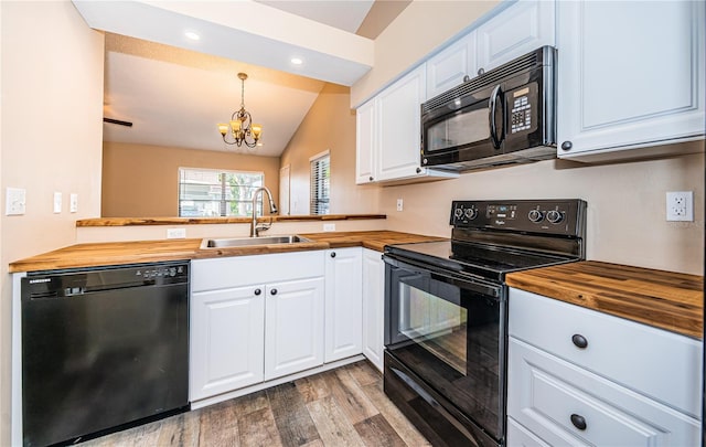 kitchen featuring wood counters, black appliances, decorative light fixtures, a notable chandelier, and white cabinetry