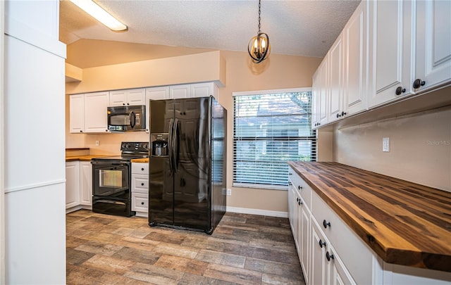 kitchen featuring wood counters, lofted ceiling, black appliances, hanging light fixtures, and white cabinetry