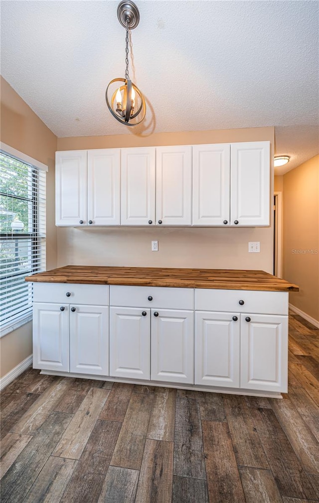 kitchen featuring pendant lighting, wood counters, white cabinetry, and dark wood-type flooring