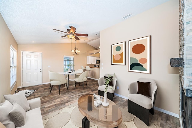 living room featuring ceiling fan with notable chandelier, a textured ceiling, hardwood / wood-style flooring, and lofted ceiling