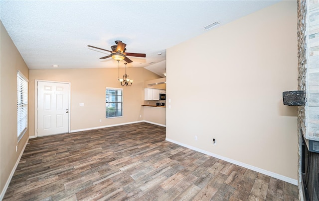 unfurnished living room featuring lofted ceiling, ceiling fan with notable chandelier, a textured ceiling, a fireplace, and wood-type flooring