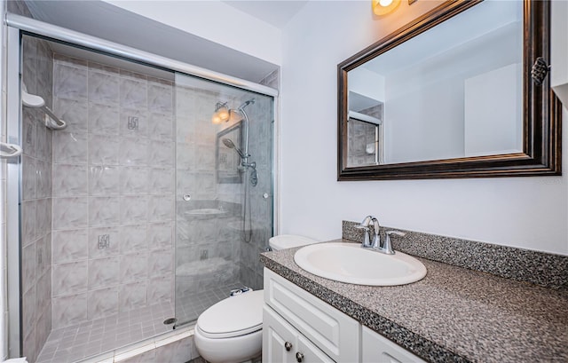 bathroom with vanity, toilet, and a shower with door