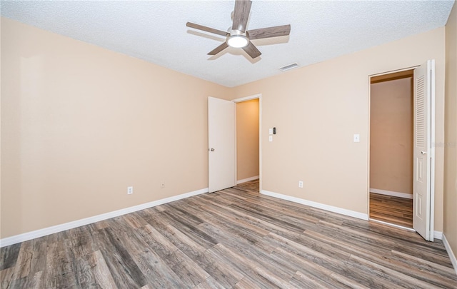 unfurnished bedroom featuring hardwood / wood-style flooring, ceiling fan, a textured ceiling, and a closet