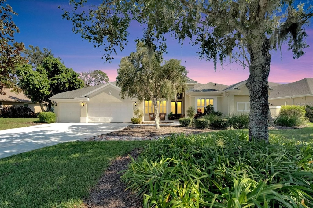 single story home featuring a garage and a yard