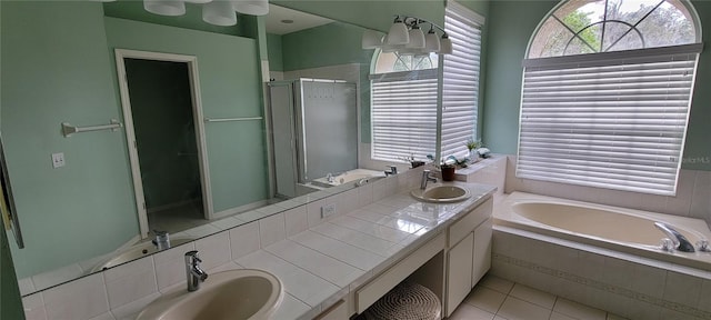 bathroom with tile patterned floors, vanity, and shower with separate bathtub