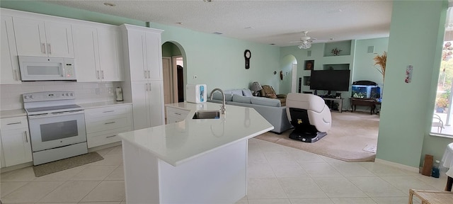 kitchen with ceiling fan, white cabinets, sink, white appliances, and a kitchen island with sink