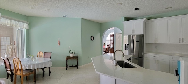 kitchen with stainless steel refrigerator with ice dispenser, sink, a wealth of natural light, and white cabinetry