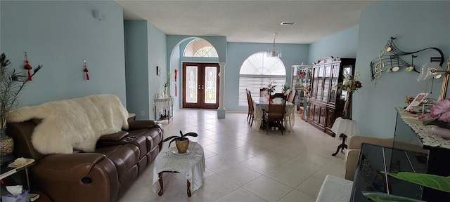 entrance foyer featuring french doors, a notable chandelier, a textured ceiling, and light tile patterned floors