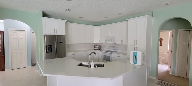 kitchen with white cabinetry, sink, light tile patterned floors, white appliances, and a textured ceiling