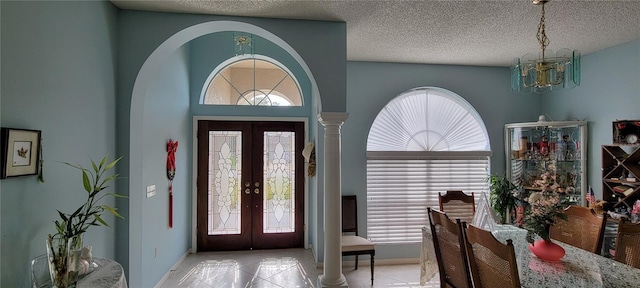 tiled entrance foyer with french doors, an inviting chandelier, and a textured ceiling