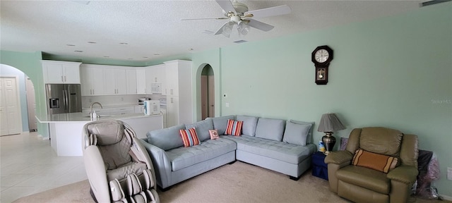 tiled living room with ceiling fan, sink, and a textured ceiling