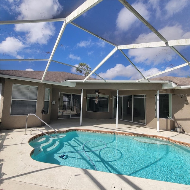 view of swimming pool featuring ceiling fan, a patio, and glass enclosure