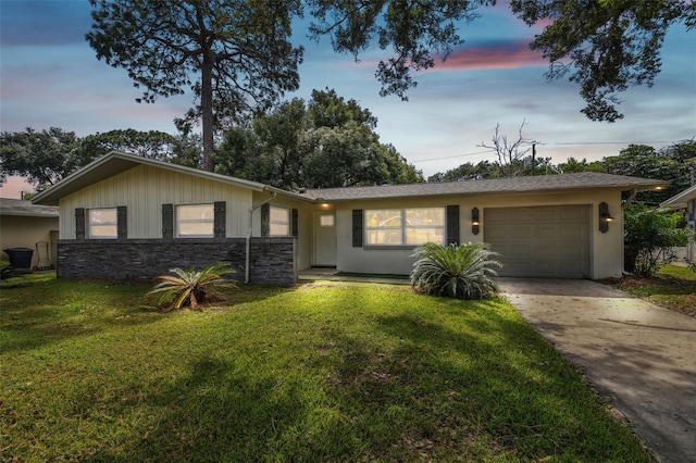 ranch-style home featuring a lawn and a garage