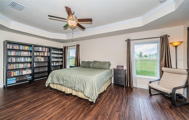 bedroom with ceiling fan, crown molding, a tray ceiling, and dark wood-type flooring