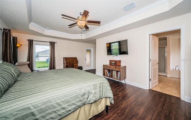 bedroom featuring ceiling fan, hardwood / wood-style floors, a raised ceiling, ensuite bath, and a textured ceiling