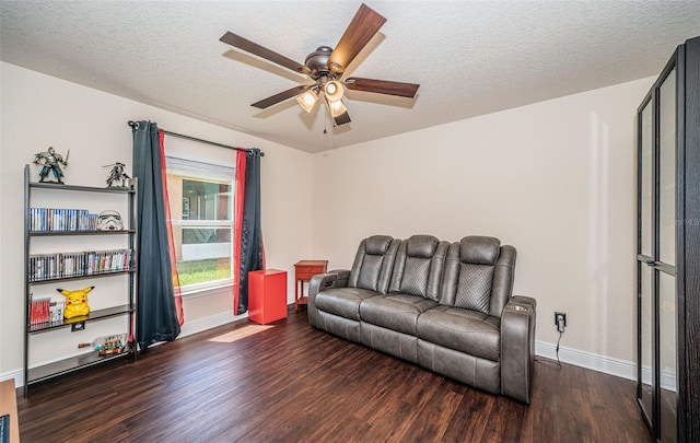 living room featuring ceiling fan, dark wood-type flooring, and a textured ceiling