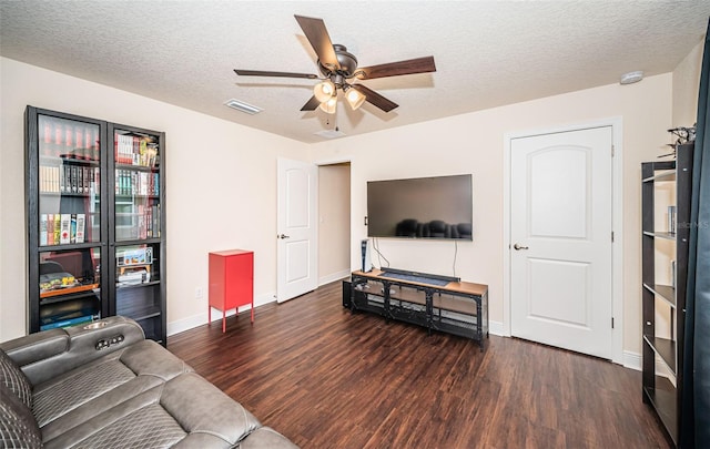 living room featuring ceiling fan, dark wood-type flooring, and a textured ceiling