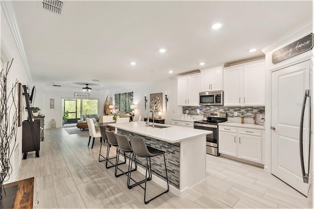 kitchen with white cabinets, sink, ornamental molding, and stainless steel appliances