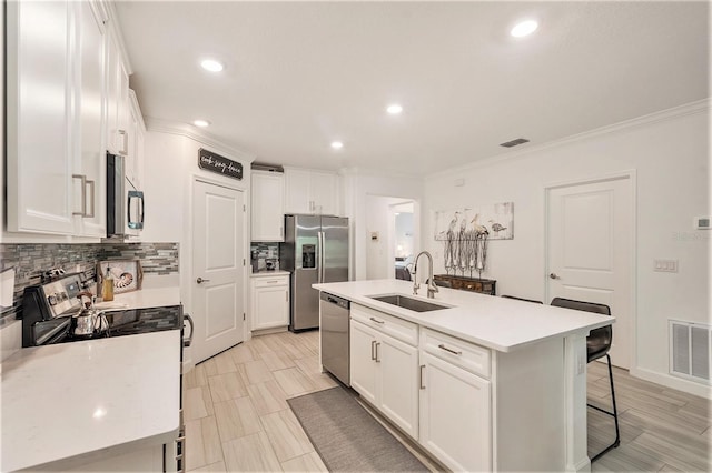 kitchen featuring stainless steel appliances, a center island with sink, sink, and white cabinets