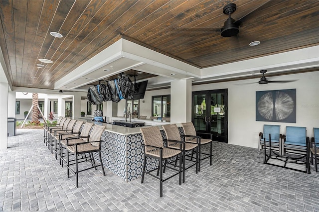 view of patio with ceiling fan and a bar