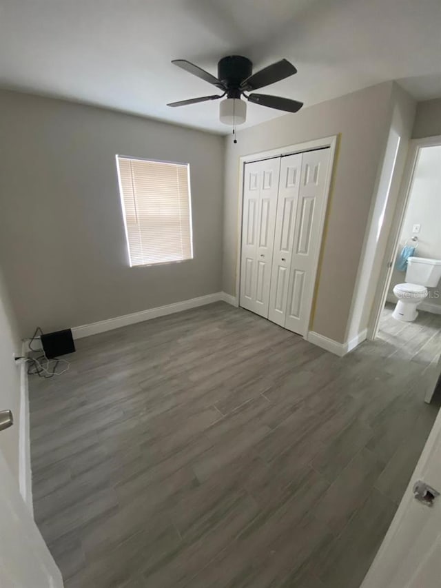 unfurnished bedroom with ensuite bath, ceiling fan, a closet, and dark hardwood / wood-style flooring