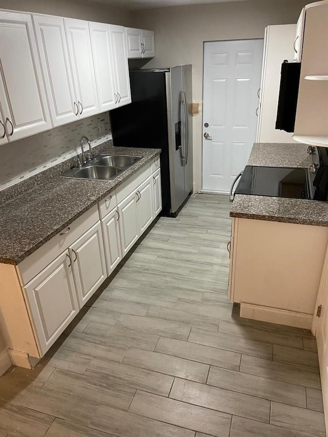 kitchen featuring white cabinets, sink, stainless steel fridge, and light hardwood / wood-style floors