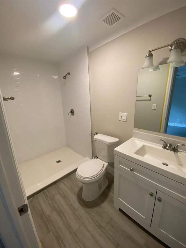 bathroom featuring walk in shower, hardwood / wood-style floors, vanity, and toilet