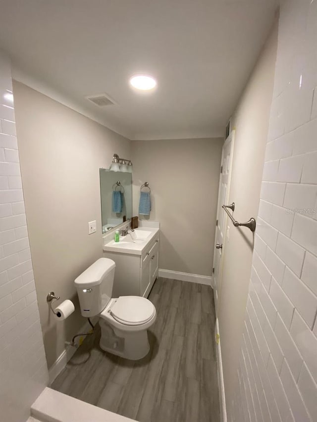 bathroom with hardwood / wood-style flooring, toilet, and vanity